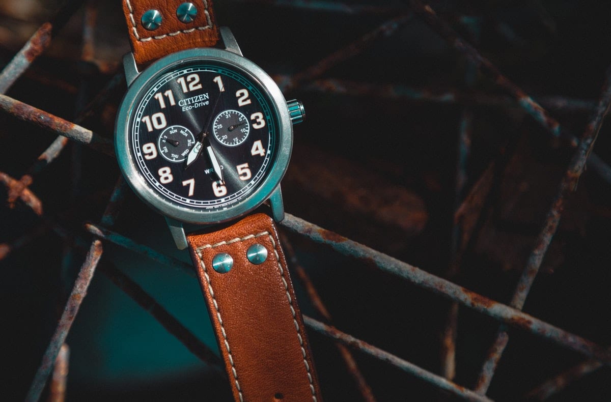 Citizen Eco-Drive mit schwarzem Zifferblatt und braunem Lederarmband auf rostigem Metallgitter