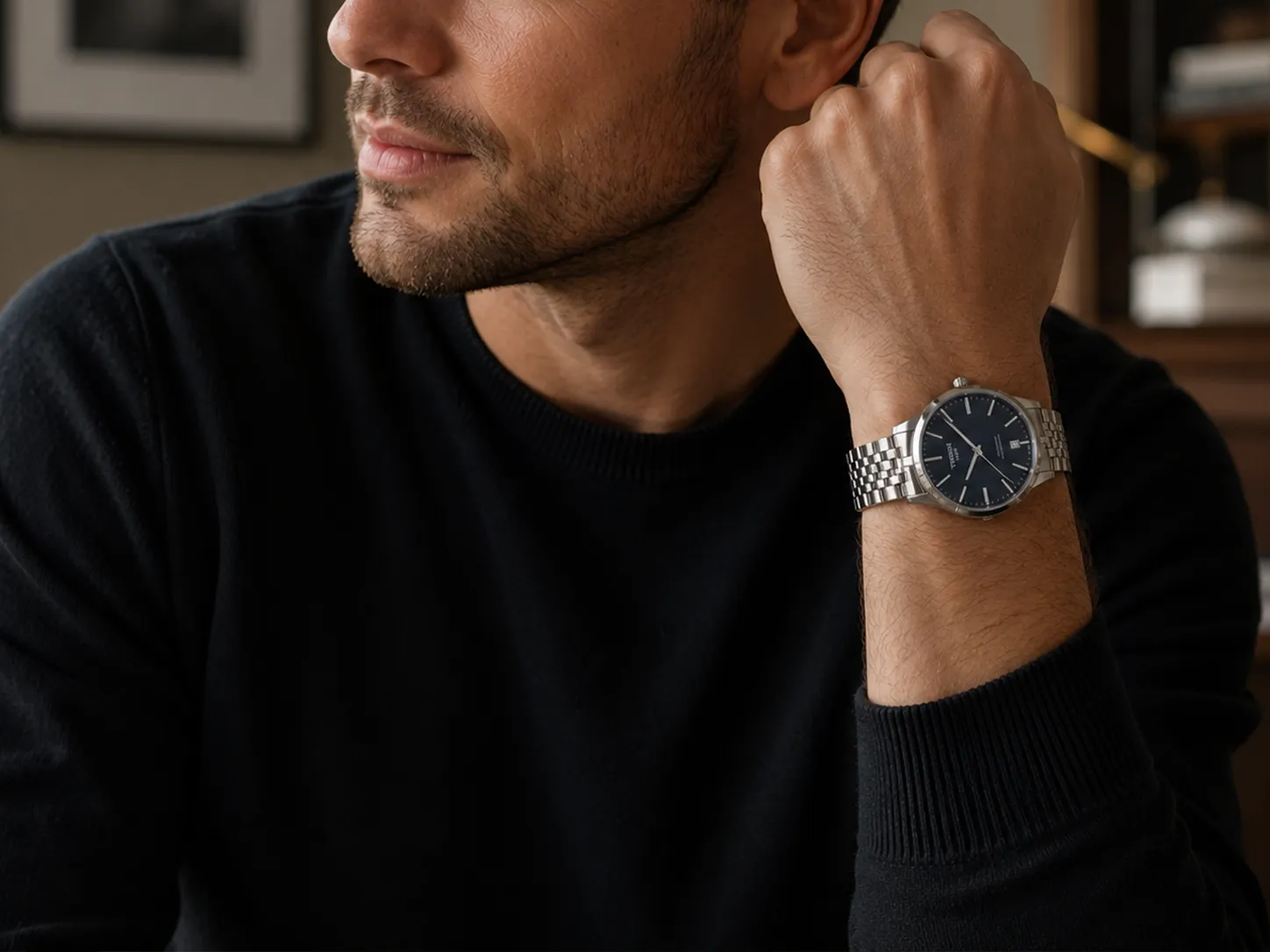 Mann im dunklen Pullover mit silberner Armbanduhr und blauem Zifferblatt
