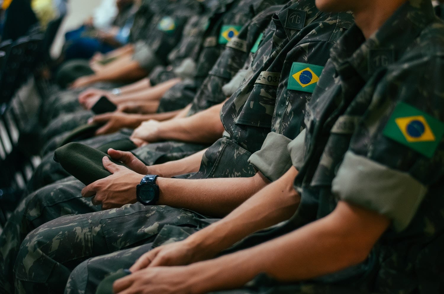 Soldaten in Tarnuniform sitzen nebeneinander, einer trägt eine schwarze Digitaluhr