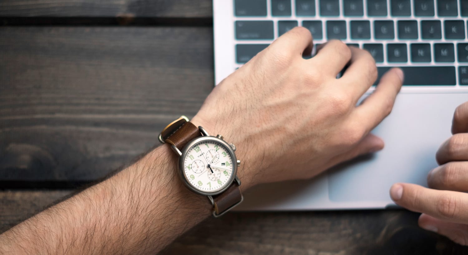 Chronograph an einem Handgelenk über der Tastatur eines Notebooks